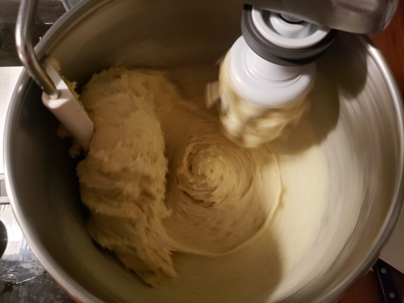 A photo looking down into the drum of an Ankarsrum Assistant stand mixer. The mixer is in motion, and there's a swirl of buttery babka dough being kneaded by the mixer's dough attachment.