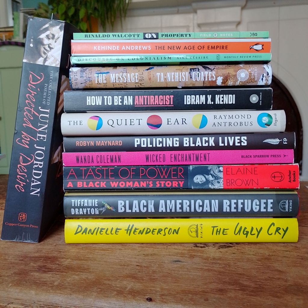 A stack of books sits on a wooden coffee table.